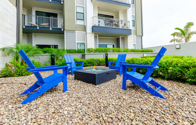 two blue chairs and a fire pit in front of an apartment building