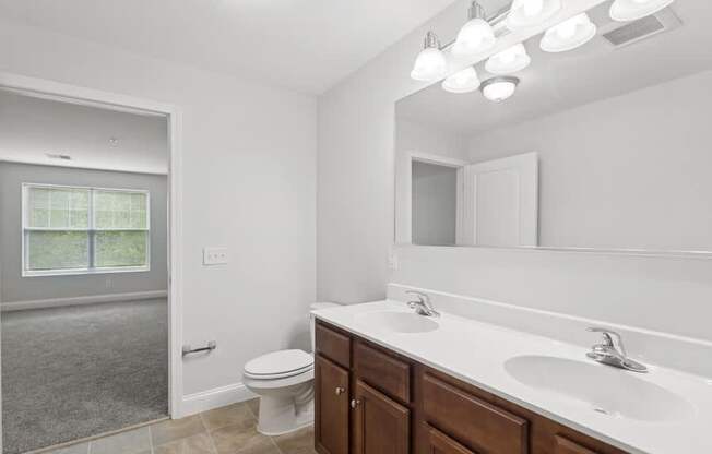 A bathroom with a toilet, sink, and mirror.