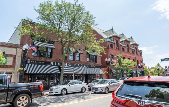 Downtown Melrose street with cars parked on the side of the road and a brick building