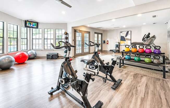 A gym with a row of exercise bikes and a row of kettlebells.