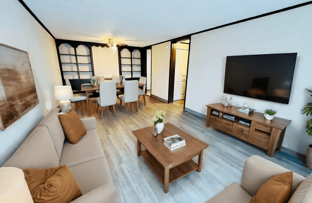 A living room with a brown sofa, a wooden coffee table, and a television.