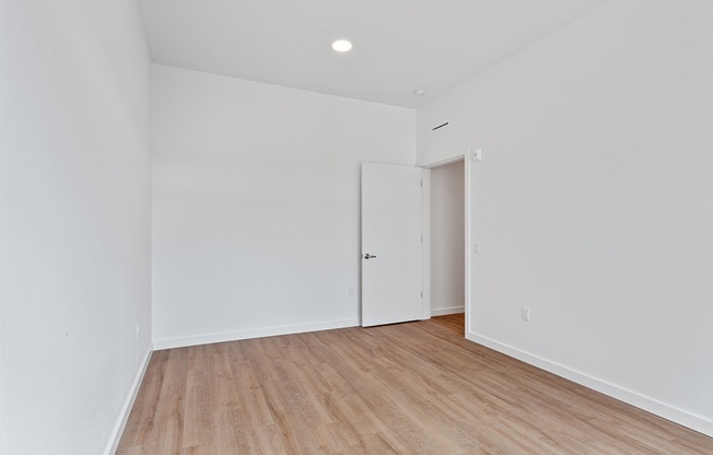 a bedroom with white walls and wood flooring