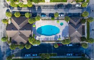 A bird's eye view of a residential area with houses, a swimming pool, and a parking lot.
