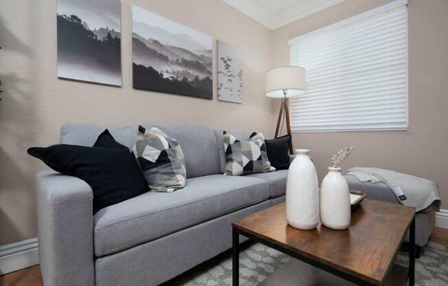 Living room of model unit with Saltillo tile flooring, crown molding and custom window blinds at the Atruim Apartments in San Diego, California.