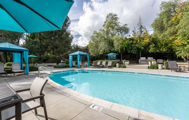 a swimming pool with chairs and umbrellas and trees