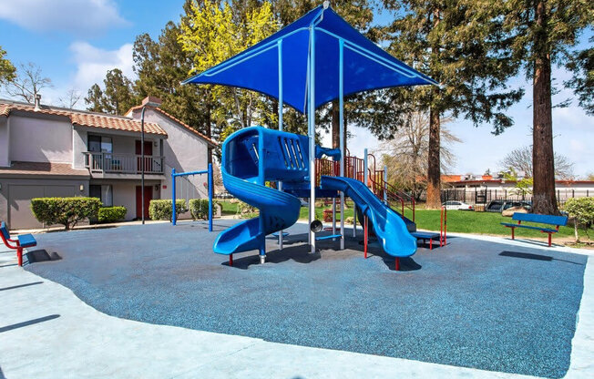 Community Playground with a Slide, Swing Set and Blue Canopy at Creek 2645 Apartments in Sacramento, CA.