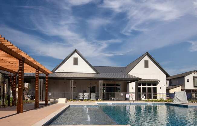 a large pool in front of a house with a blue sky