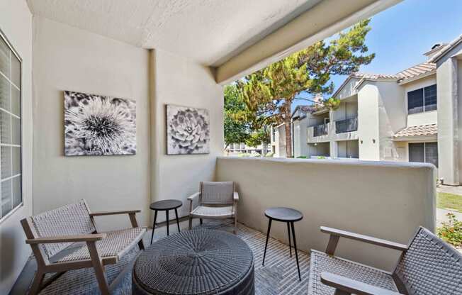 a balcony with a table and chairs and a tree in the background