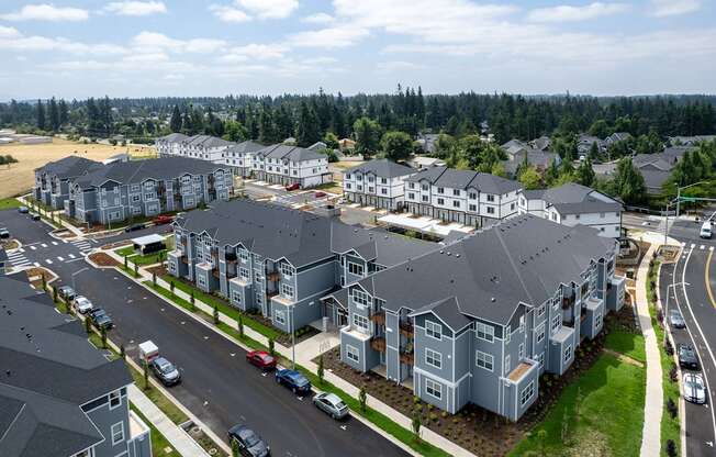 A large residential complex with multiple buildings and cars parked in front.