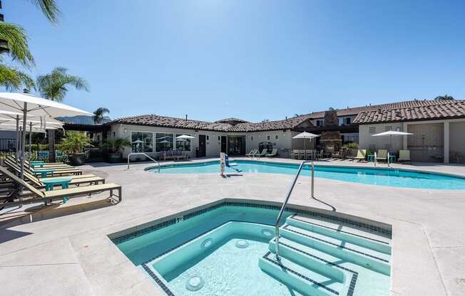 a swimming pool and spa with chairs and umbrellas