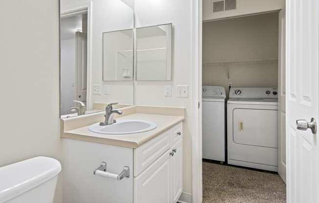 a bathroom with a sink and a mirror and a laundry room