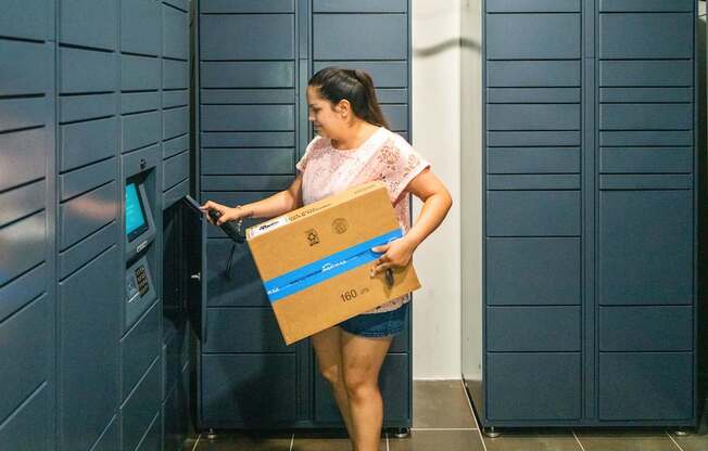 A woman is using a self-service machine with a package.