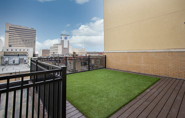 a small astroturf lawn on a balcony with a city in the background