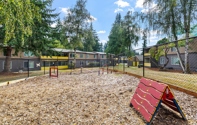 A playground with a red slide and a fence in the background.