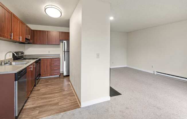 an empty kitchen and living room with wooden cabinets and stainless steel appliances