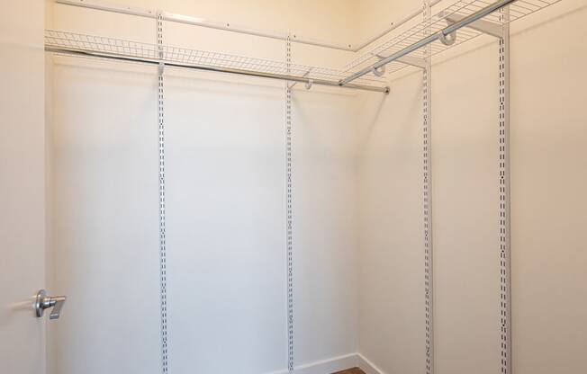 a walk in closet with white walls and a metal rack on the wall