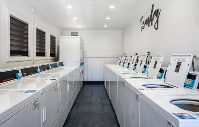 a laundry room filled with lots of white washing machines