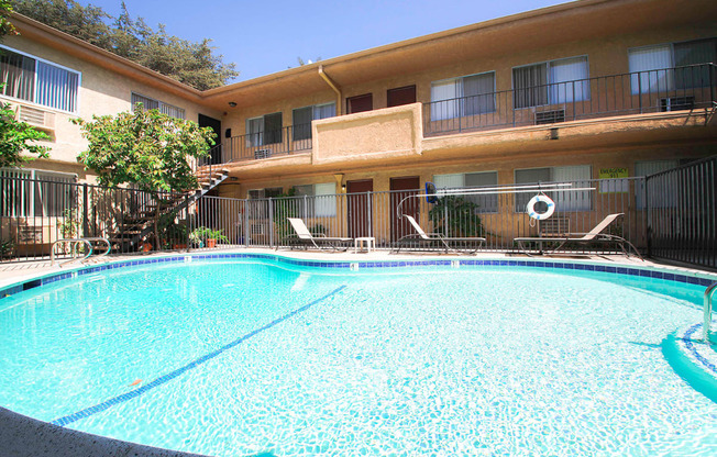 View of gated community pool with lounging space.