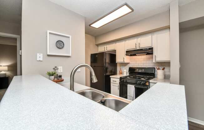 a kitchen with white countertops and a large white island with a stainless steel sink