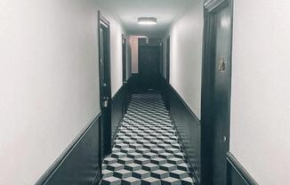 a long hallway with black and white flooring and black doors