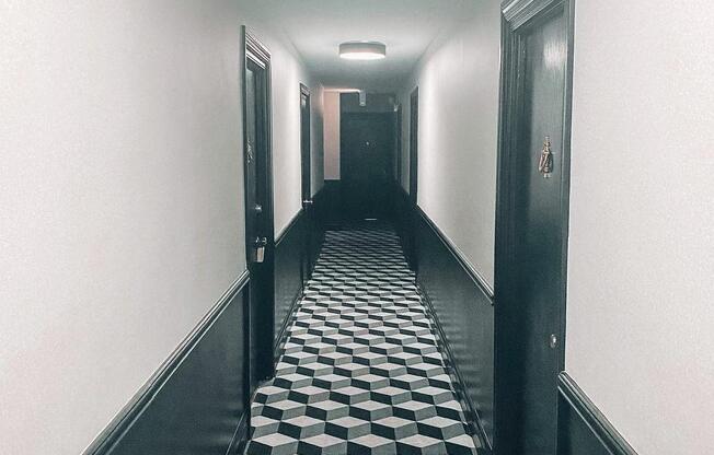 a long hallway with black and white flooring and black doors