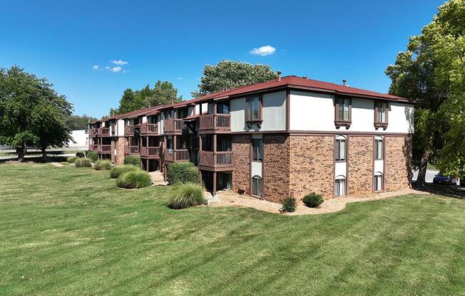 A brick building with a red roof and white exterior walls with windows and balconies at Old Monterey Apartments, Springfield, MO