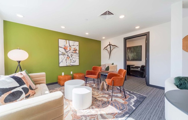 A living room with a white couch, orange chairs, and a rug.
