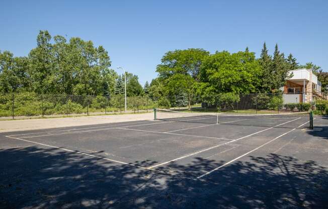 a tennis court with trees and a house in the background