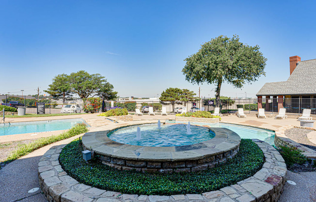 an outdoor pool with a fountain and a building in the background