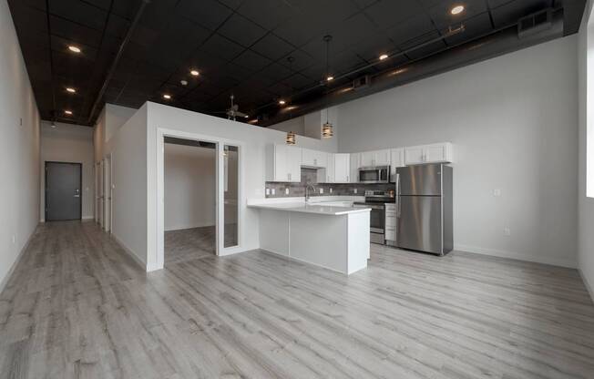 A modern kitchen with white cabinets and a wooden floor.