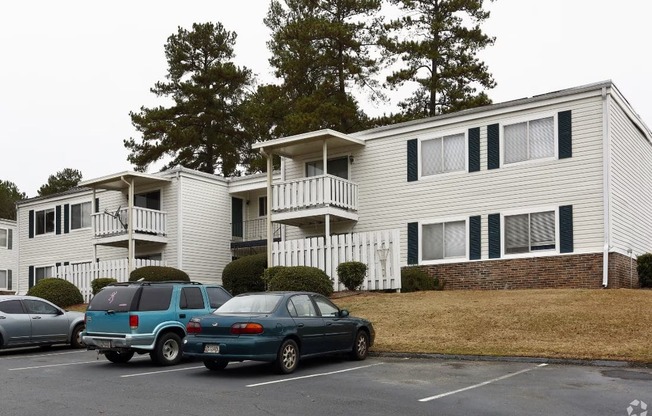 an apartment building with cars parked in a parking lot