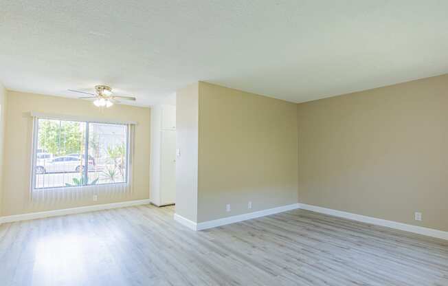 an empty living room with wood floors and a ceiling fan