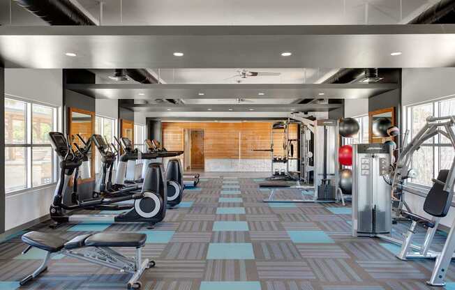 A gym with a variety of equipment including treadmills, weights, and exercise machines at Denim Scottsdale, Scottsdale, AZ