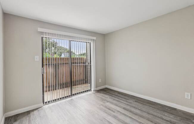 A room with a sliding door leading to a backyard.