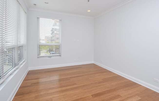 a living room with white walls and wood floors and a window