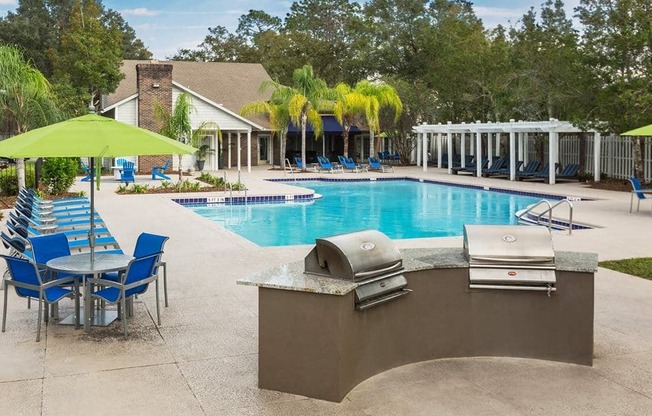 a swimming pool with chairs and a bar with a grill