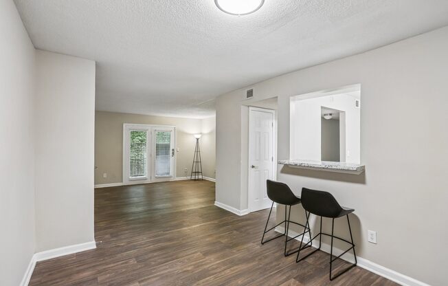 A room with a wooden floor and two black chairs.
