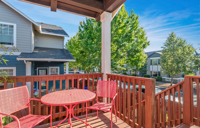 A red table and chairs are on a wooden deck at The Landing Apartments and Townhomes, Oregon, 97045