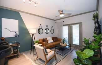 A living room with a brown couch, a black floor lamp, and a painting on the wall.
