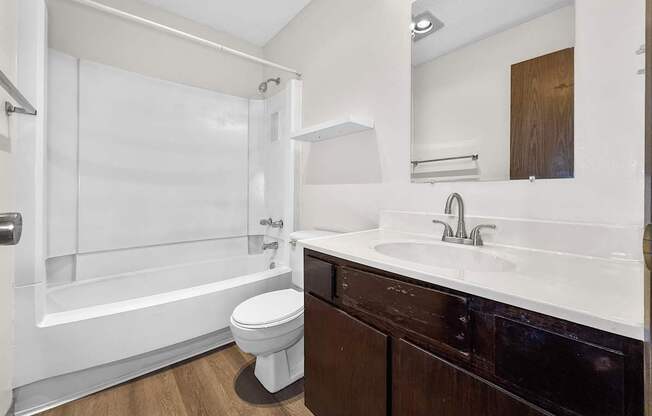 A white toilet sits in a bathroom with a white tub and sink.