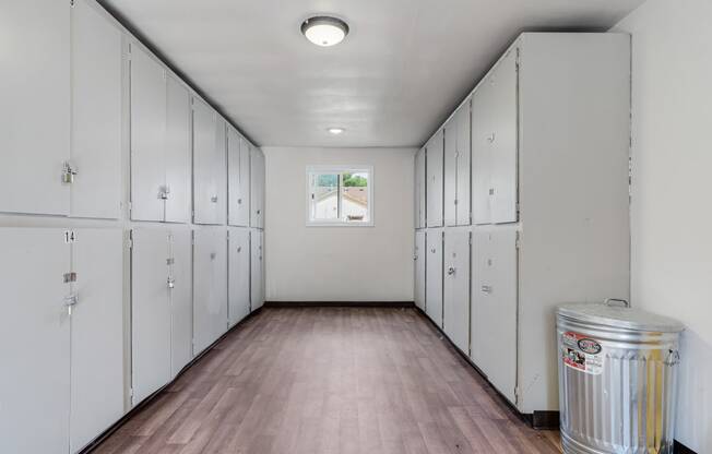 a locker room with white lockers and a silver trash can