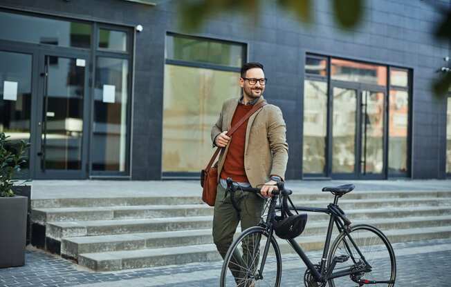 a man walking his bike down the street