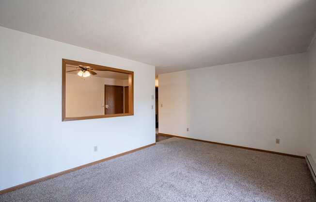 an empty living room with white walls and a large mirror. Fargo, ND Southview Village Apartments