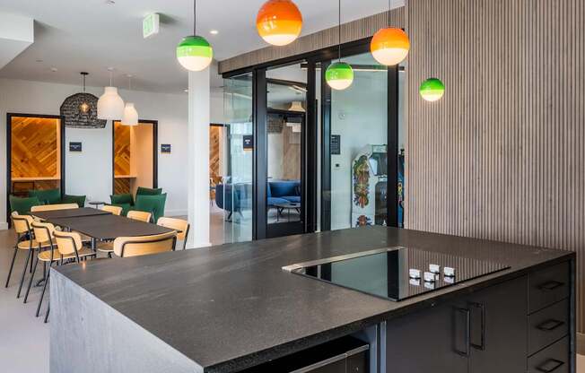 A modern kitchen with a black countertop and green chairs.