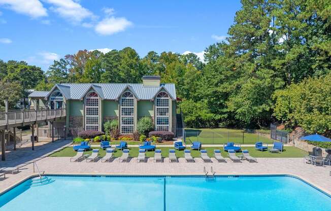 a swimming pool with chaise lounge chairs and a house in the background