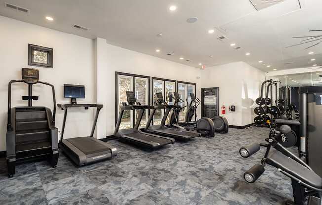 A gym with treadmills, weights, and exercise equipment.