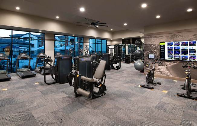 a spacious fitness center with cardio equipment and a large window