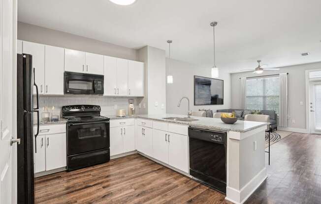 A modern kitchen with black appliances and white cabinets.