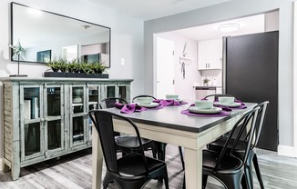 a dining area with a table and chairs and a kitchen in the background