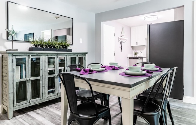 a dining area with a table and chairs and a kitchen in the background